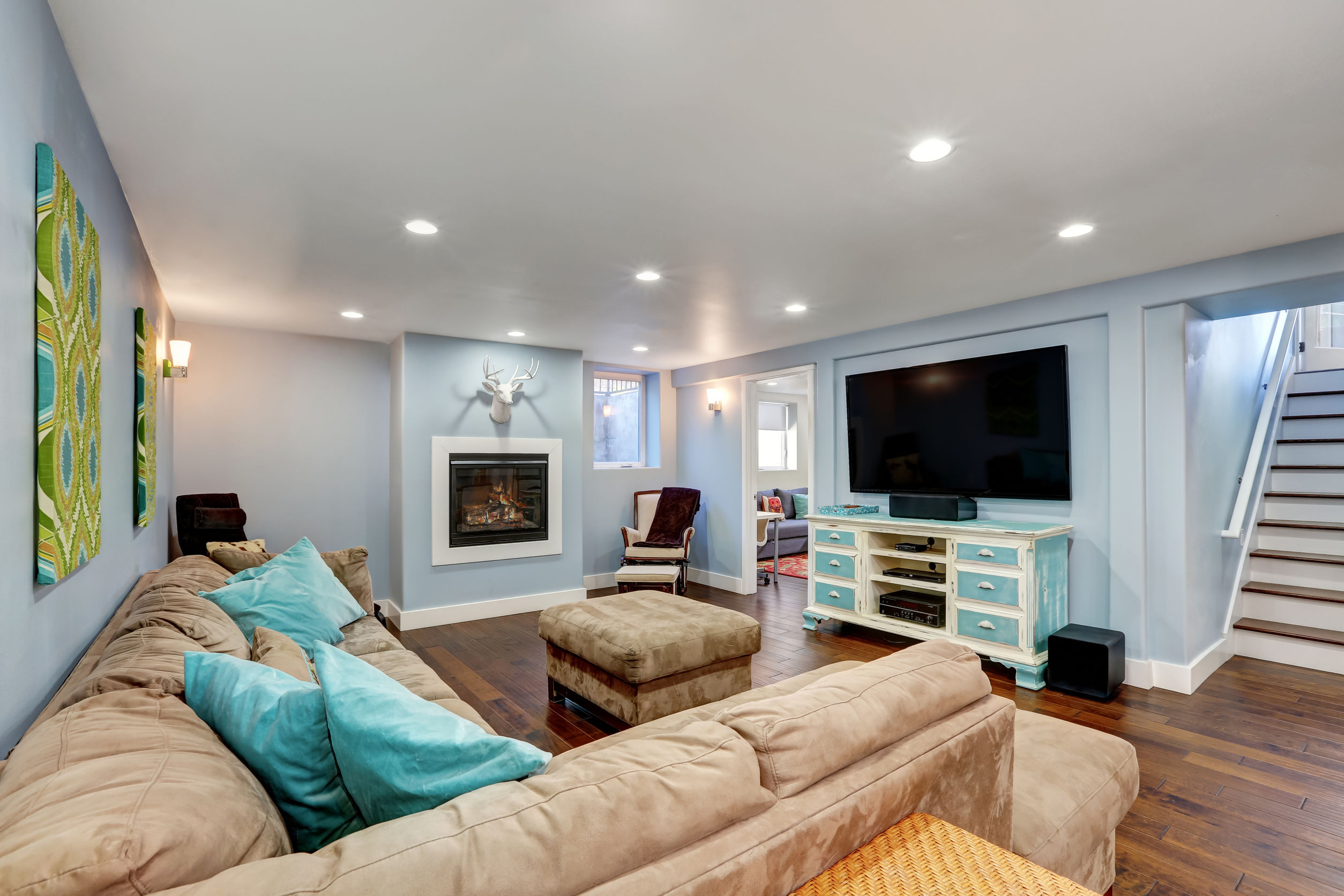 62161255 - pastel blue walls in basement living room interior. large corner sofa with blue pillows and ottoman. vintage white and blue tv cabinet. northwest, usa